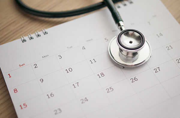 The image shows a calendar with the month April highlighted, placed next to a stethoscope, suggesting a medical theme.
